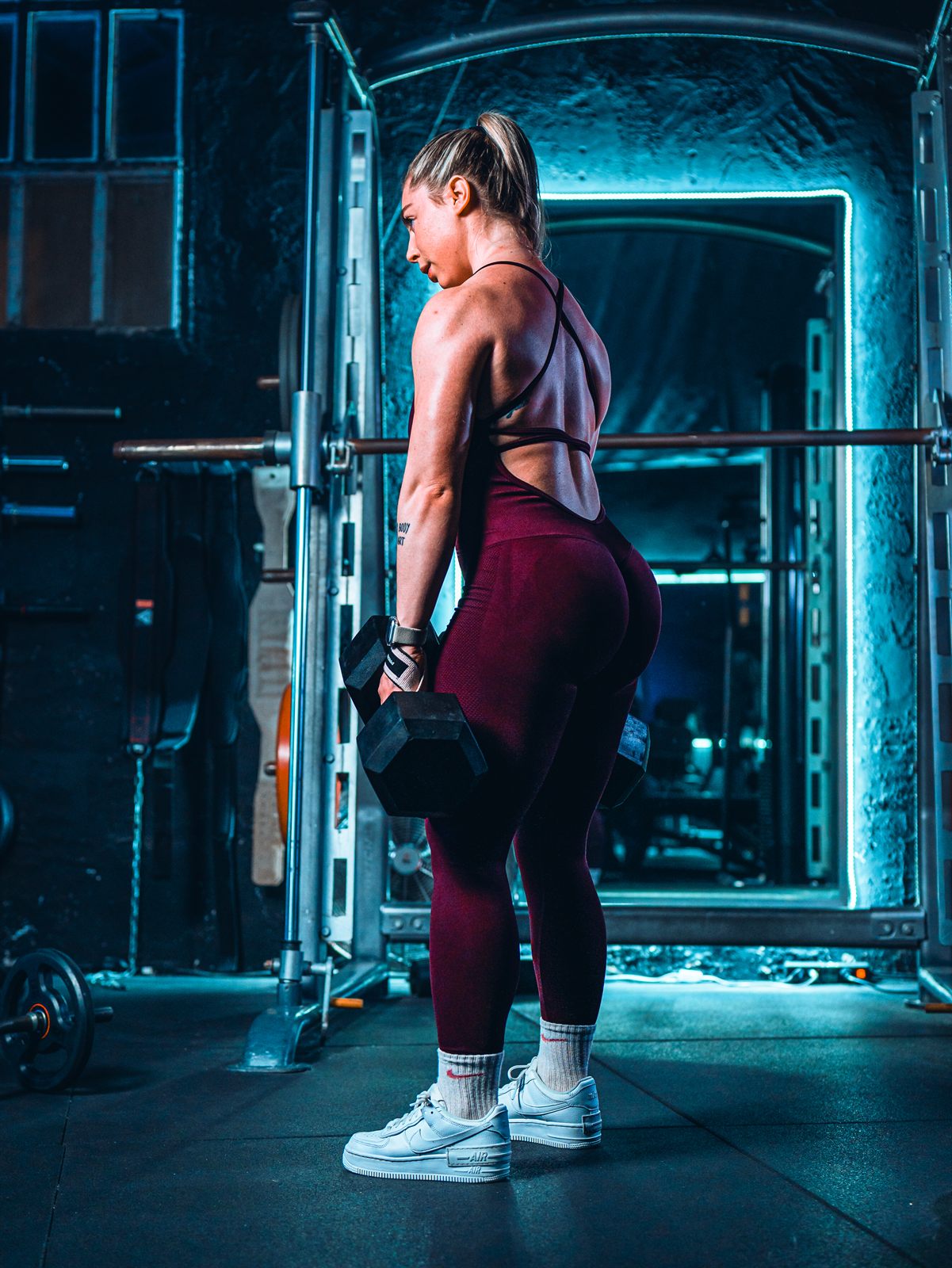 Judith Ramos entrenando con mancuernas en la sala de Ímpetu, con las luces azules del gimnasio